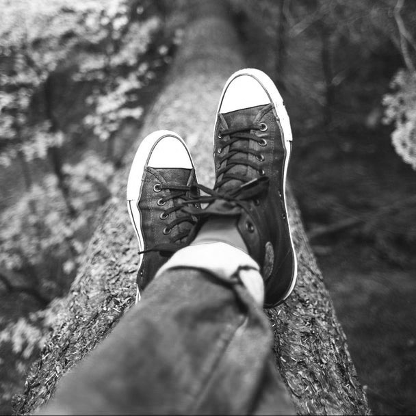 Sitting on a fallen log in the woods, legs stretched out along the trunk